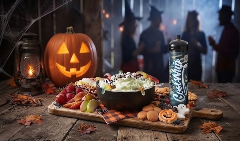 Cool Whip Cream Halloween dip board with a black bowl of green dip topped with candy eyeballs and gummy worms beside fruit and cookies